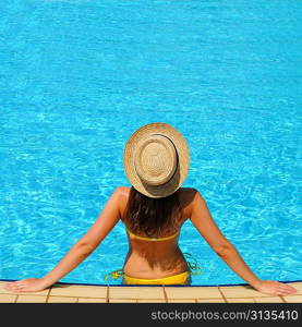 Woman in hat relaxing at the pool