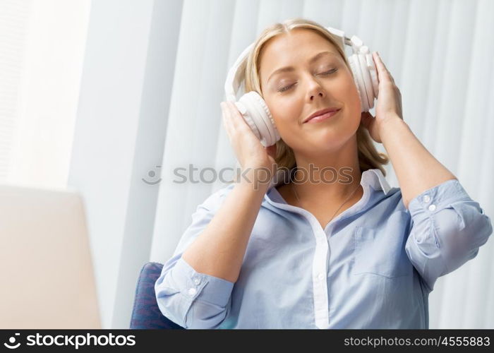 Woman in headphones sitting at desk in office