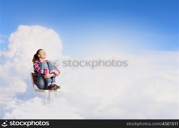 Woman in heaven. Young woman sitting in chair on cloud high in sky