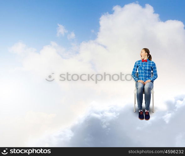 Woman in heaven. Young woman sitting in chair on cloud high in sky