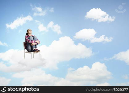 Woman in heaven. Young woman sitting in chair on cloud high in sky