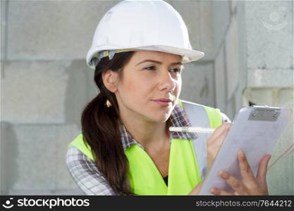 woman in helmet with clipboard inside construction site