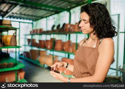 Woman in her ceramic shop using her smart phone