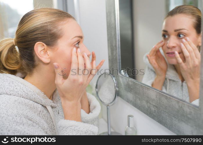 woman in her thirties checking her face for wrinkles