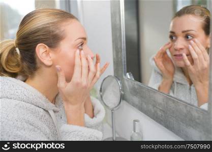 woman in her thirties checking her face for wrinkles