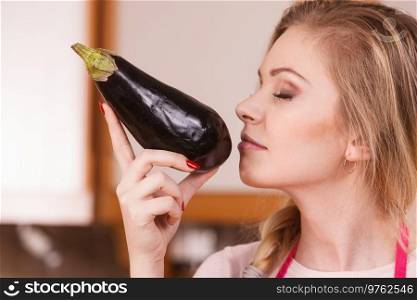 Woman in holding and smelling delicious eggplant vegetable. Healthy lifestyle, eating veggies, superfood.. Woman holding and smelling eggplant