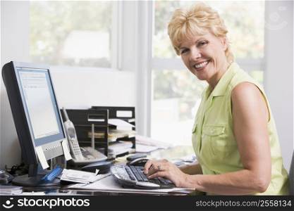 Woman in home office at computer smiling