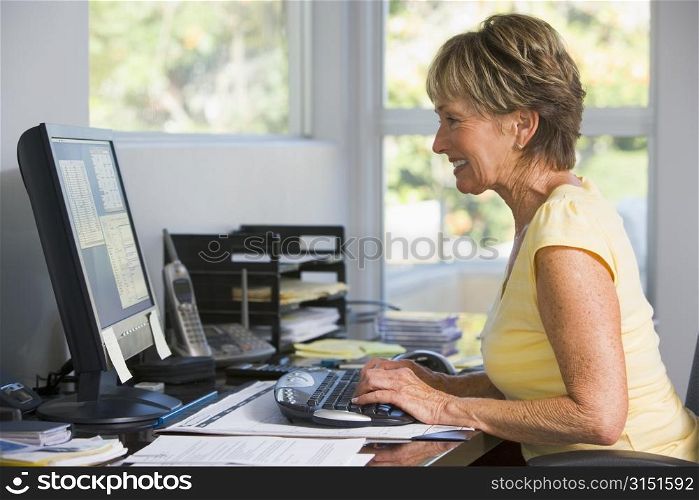 Woman in home office using computer smiling