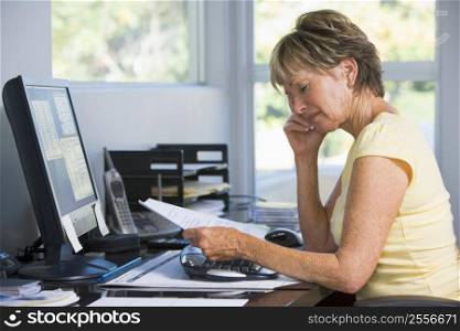 Woman in home office with computer and paperwork