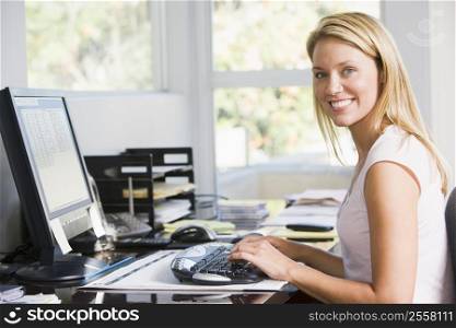 Woman in home office with computer smiling