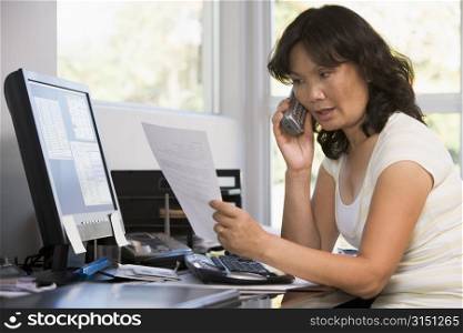 Woman in home office with paperwork using telephone