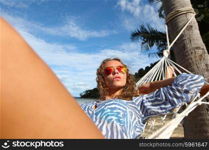 Woman in hummock on tropical beach. Young beautiful woman resting in hummock on tropical beach