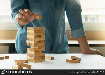 Woman in jeans shirt holding blocks wood game Building a small brick wall Risk concept.