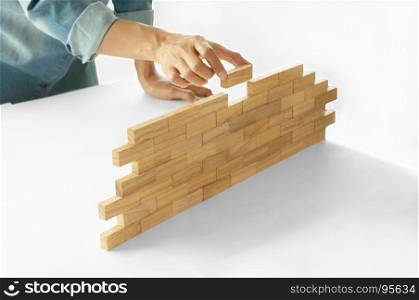 Woman in jeans shirt holding blocks wood game Building a small brick wall Risk concept
