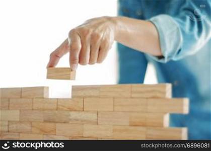 Woman in jeans shirt holding blocks wood game (jenga) Building concept