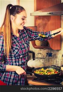 Woman in kitchen cooking stir fry frozen vegetables and tasting. Girl frying making delicious risotto. Dinner food meal.. Woman frying frozen vegetables. Stir fry.