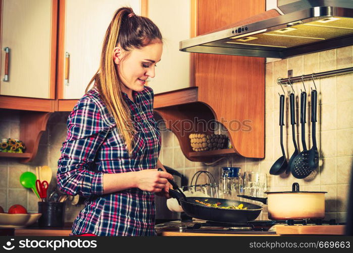Woman in kitchen cooking stir fry frozen vegetables. Girl frying making delicious risotto. Dinner food meal. Instagram filter.. Woman frying frozen vegetables. Stir fry.