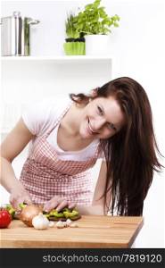 woman in kitchen cutting paprika. happy young woman in kitchen cutting paprika