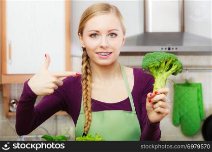 Woman in kitchen holding green fresh broccoli. Young housewife cooking. Healthy eating, vegetarian food, dieting and people concept.. Woman in kitchen with green fresh broccoli