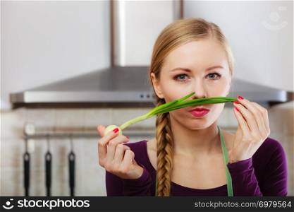 Woman in kitchen holding green fresh chive with onion. Young housewife cooking. Healthy eating, vegetarian food, dieting and people concept.. Woman in kitchen holds green fresh chive