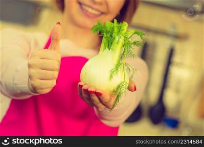 Woman in kitchen holding green fresh raw fennel bulb vegetable. Housewife cooking meal. Healthy eating, vegetarian food, dieting concept.. Woman holding fennel bulb