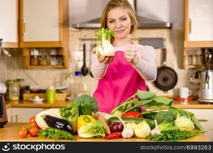 Woman in kitchen holding green fresh raw fennel bulb vegetable. Housewife cooking meal. Healthy eating, vegetarian food, dieting concept.. Woman holding fennel bulb