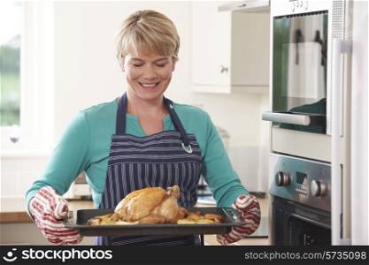 Woman In Kitchen Holding Tray With Roast Chicken