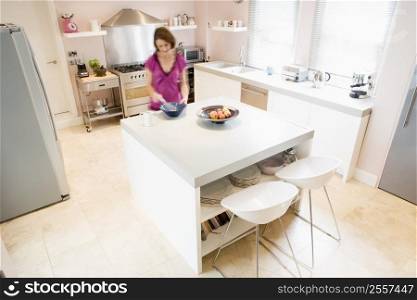 Woman in kitchen whisking on counter