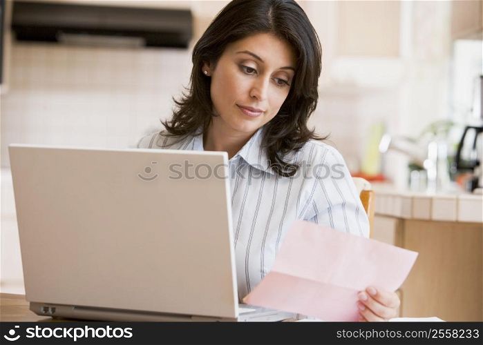 Woman in kitchen with laptop