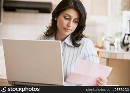 Woman in kitchen with laptop