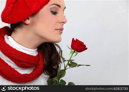 Woman in knitted hat smelling rose