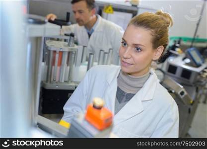 Woman in labcoat by industrial machinery