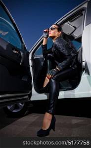 Woman in leather clothes with car