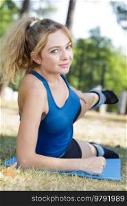 woman in leggings stretching on fitness mat outdoors