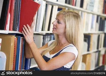 Woman in library pulling book off a shelf (depth of field)