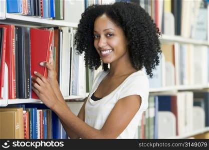 Woman in library pulling book off a shelf (depth of field)