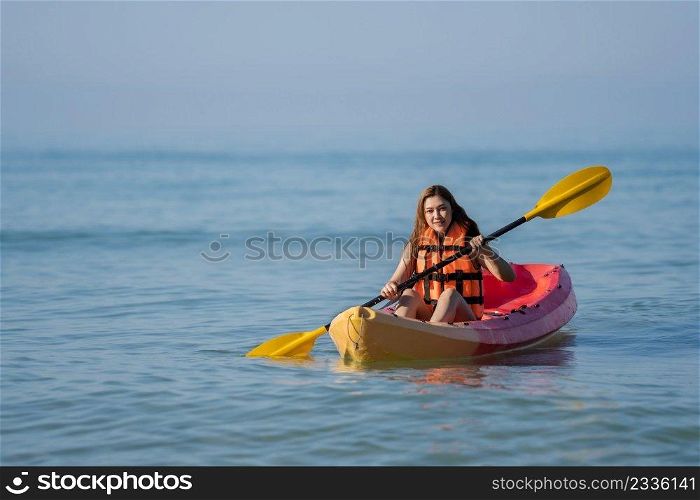 woman in life jacket paddling a kayak boat in the sea