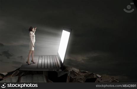 Woman in light of laptop screen. Young businesswoman standing on keyboard of big laptop