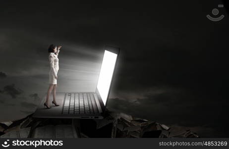 Woman in light of laptop screen. Young businesswoman standing on keyboard of big laptop