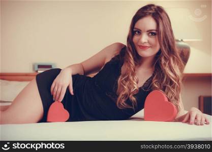 Woman in lingerie in bed. Valentines day love.. Seductive woman wearing lingerie in bed at home. Attractive sensual young girl with heart shape boxes. Female underwear fashion. Valentines day love.