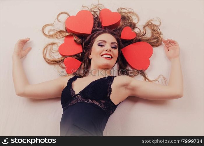 Woman in lingerie in bed. Valentines day love.. Happy woman wearing lingerie in bed at home. Attractive seductive young girl with heart shape boxes around head. Female underwear fashion. Valentines day love.
