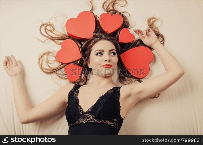 Woman in lingerie in bed. Valentines day love.. Happy woman wearing lingerie in bed at home. Attractive seductive young girl with heart shape boxes around head. Female underwear fashion. Valentines day love.