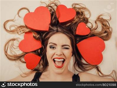Woman in lingerie in bed. Valentines day love.. Happy woman wearing lingerie in bed at home winking. Attractive seductive young girl with heart shape boxes around head. Female underwear fashion. Valentines day love.