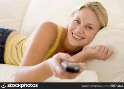 Woman in living room holding remote control smiling