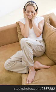 Woman in living room listening to headphones smiling