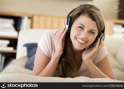 Woman in living room listening to headphones smiling