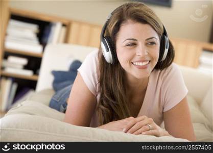 Woman in living room listening to headphones smiling