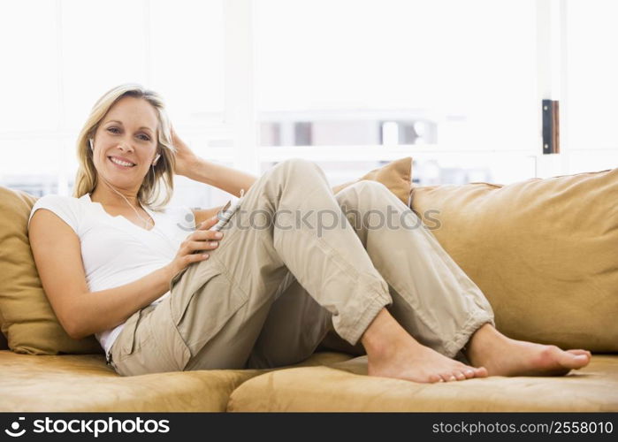 Woman in living room listening to MP3 player smiling