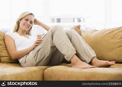 Woman in living room listening to MP3 player smiling