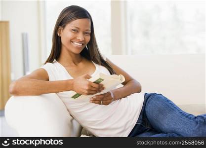 Woman in living room reading book smiling